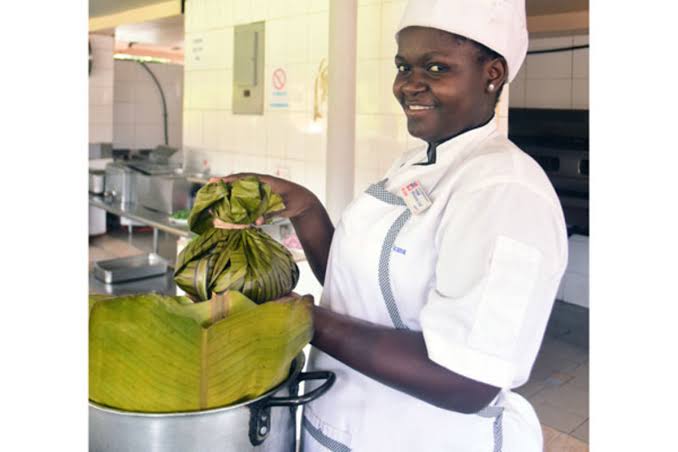 A Ugandan chef holding a luwombo parcel wrapped in banana leaves